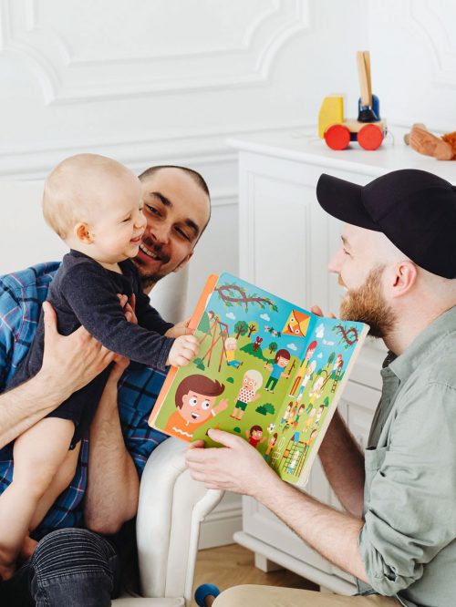 Schwule Väter lesen ihrem Kind aus Kinderbuch vor